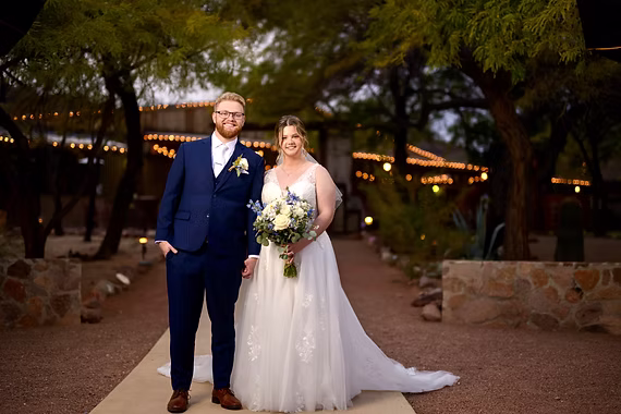 Newlyweds on the courtyard path under string lights